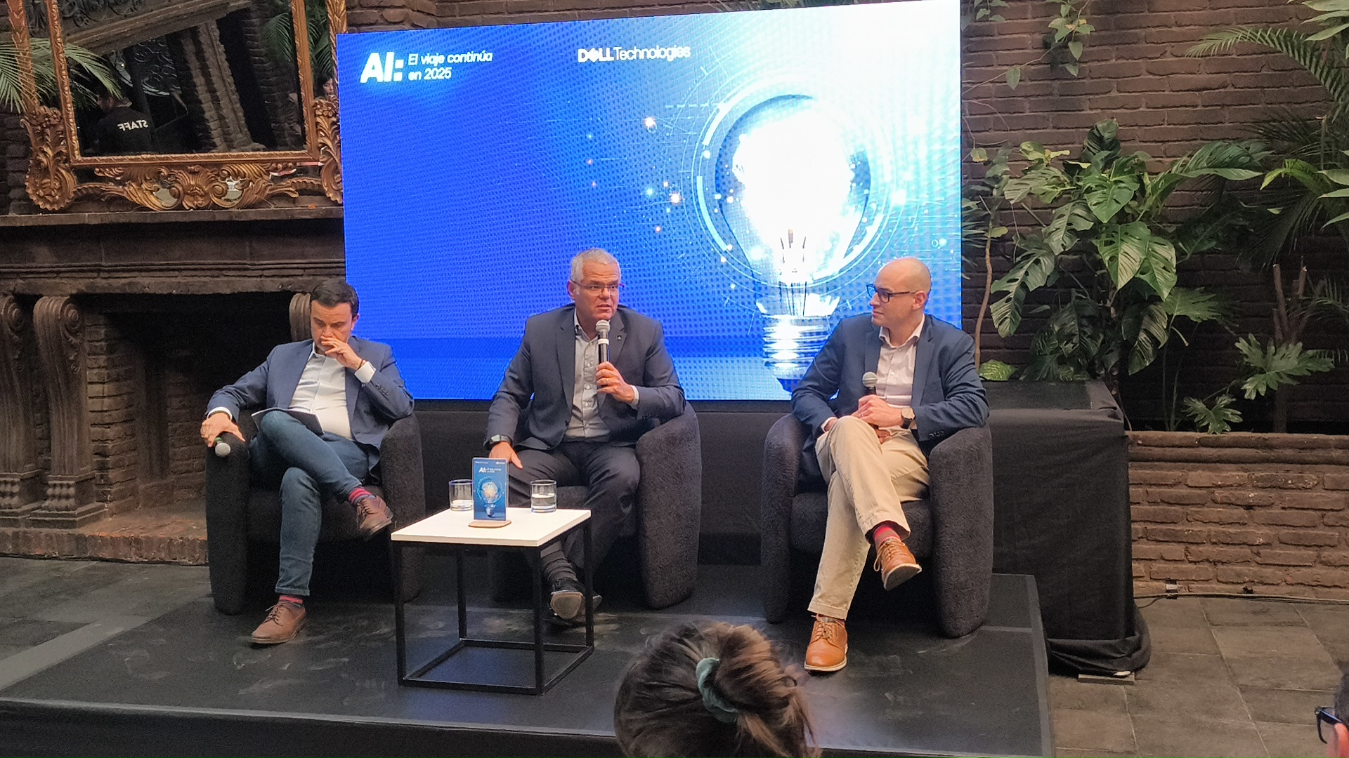 Tres expertos sentados en un escenario conversando sobre el futuro de la Inteligencia Artificial, frente a una pantalla que muestra el texto ‘AI: El viaje continúa en 2025’ junto al logotipo de Dell Technologies.